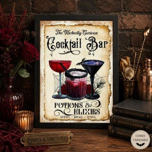 K&ouml;nnte beinhalten: Ein gerahmter Kunstdruck mit dem Titel The Wickedly Curious Cocktail Bar Potions & Elixirs Spirits Brews Tonics. Das Bild zeigt drei Cocktailgl&auml;ser, eine kleine Fledermaus, Spinnennetze und rote Rosen auf einem Hintergrund im Pergamentstil.