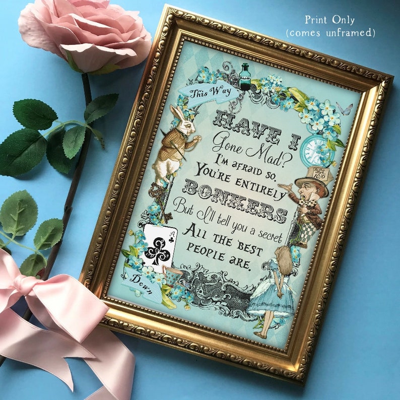 May include: A framed print with a blue background featuring Alice in Wonderland characters, including the White Rabbit and the Mad Hatter. The print includes the text "Have I Gone Mad? I'm afraid so. You're entirely bonkers. But I'll tell you a secret. All the best people are."