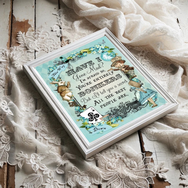 May include: A framed print with a blue background featuring a quote from Alice in Wonderland. The quote reads "Have I Gone Mad? I'm afraid so. You're entirely bonkers. But I'll tell you a secret. All the best people are."
