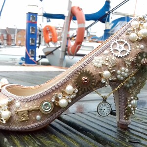 May include: A pair of gold and ivory high-heeled shoes decorated with pearls, gears, and a small pocket watch charm.