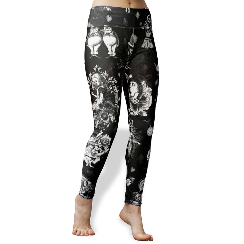 May include: Black leggings with a white print of characters from Alice in Wonderland. The print includes the Queen of Hearts, the Mad Hatter, the Cheshire Cat, and the White Rabbit.