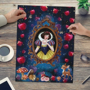 May include: A jigsaw puzzle featuring a whimsical illustration of Snow White, surrounded by red apples and a deer. The princess is framed in a gold ornate mirror, set against a dark blue starry background.