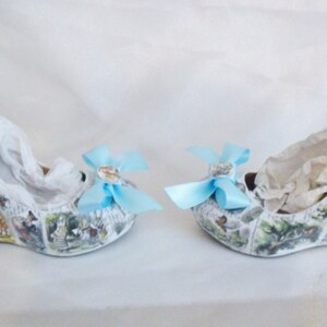 May include: A pair of white wedge shoes with a blue bow on each shoe. The shoes are covered in a print of a storybook illustration.
