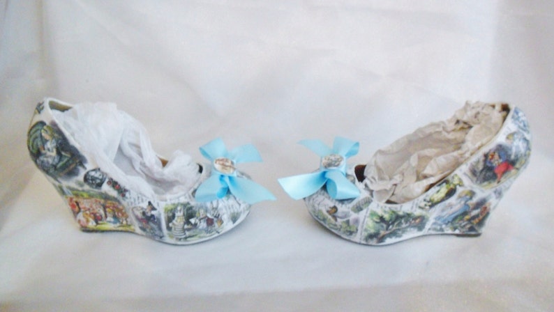 May include: A pair of white wedge shoes with a blue bow on each shoe. The shoes are covered in a print of a storybook illustration.