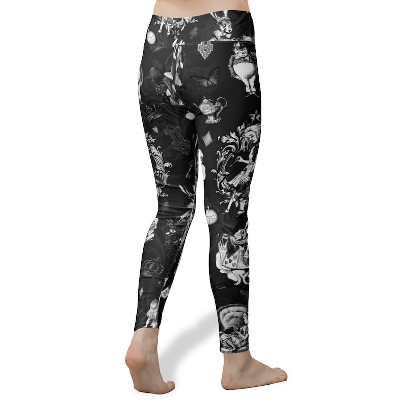 May include: Black leggings with a white print of Alice in Wonderland characters and symbols. The print includes the Mad Hatter, the Cheshire Cat, playing cards, and a teapot.
