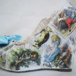 May include: White wedge shoe with a colorful Alice in Wonderland print featuring characters like the Cheshire Cat, the Mad Hatter, and the Queen of Hearts.