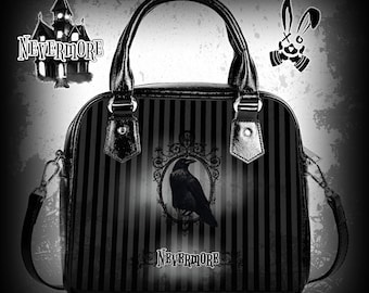 May include: Black and white striped handbag with a black raven illustration in a silver frame. The bag has a top handle and a shoulder strap. The text "Nevermore" is printed on the bag.