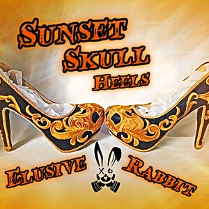 May include: A pair of black high-heeled shoes with gold embroidery and a skull design on the toe. The shoes are called "Sunset Skull Heels" and are made by "Elusive Rabbit".