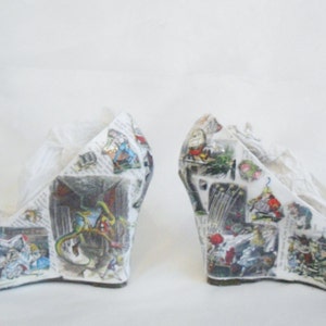 May include: A pair of white wedge shoes with a blue bow. The shoes are covered in a collage of images from a book, possibly Alice in Wonderland.