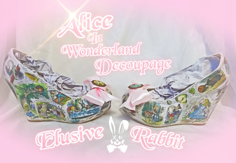 May include: A pair of white wedge shoes decorated with a decoupage design featuring scenes from Alice in Wonderland. The shoes have pink bows and the text "Alice in Wonderland Decoupage Elusive Rabbit" is printed on the background.
