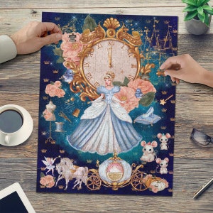 Może przedstawiać: Błękitna i biała układanka z postacią Kopciuszka, zegarem, karetą i myszami. Układanka ma niebieskie, gwiaździste tło z złotymi akcentami.