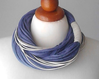 May include: A purple and white infinity scarf made of soft fabric. The scarf is displayed on a white mannequin bust.