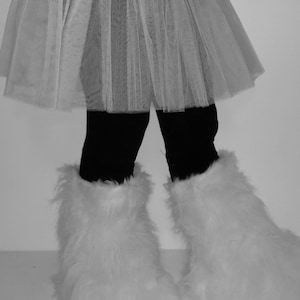 Può includere: Una gonna tutu di tulle bianco con leggings neri e scaldagambe di pelliccia bianca.