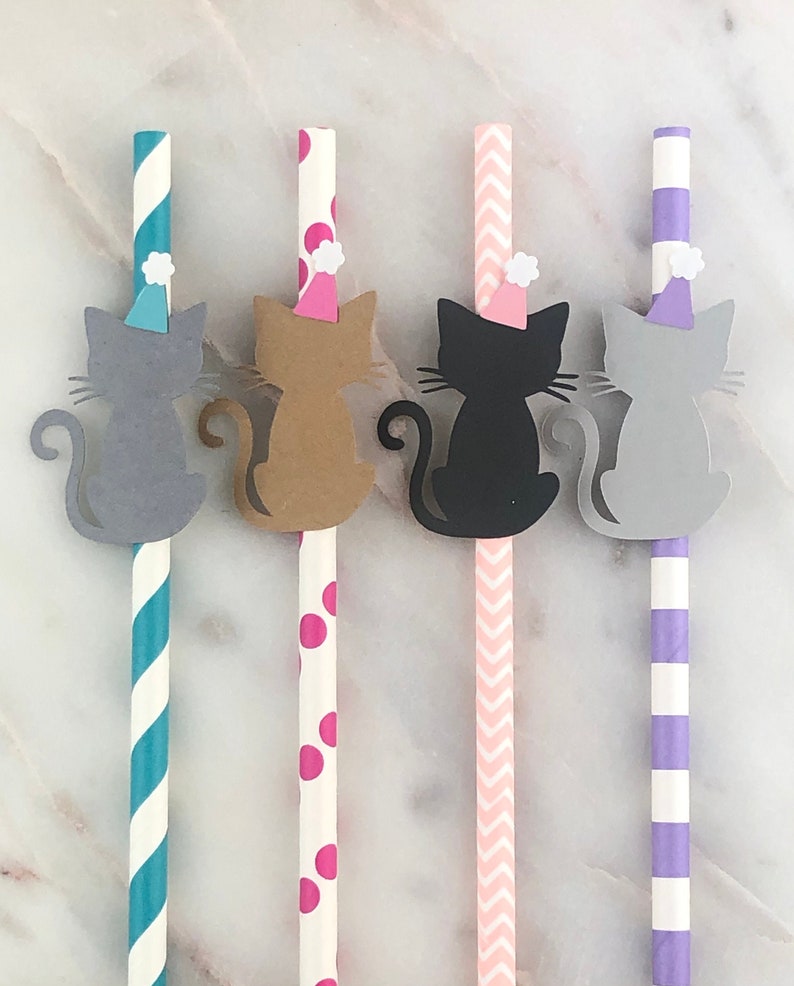 May include: Four paper straws with cat cutouts attached. The straws have different patterns: teal and white stripes, pink and white polka dots, pink and white chevron, and purple and white stripes. The cats are gray, brown, black, and gray, and each has a small white party hat.