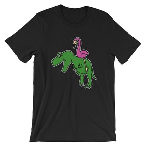フラミンゴがT-Rexに乗っている面白いユニセックスシャツ | かわいい漫画動物グラフィッククールユーモアTシャツ | 最高のお土産半袖Tシャツ