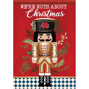 May include: A Christmas-themed decorative print featuring a gold and black nutcracker soldier with a black mustache and curly hair. The text "WE'RE NUTS ABOUT Christmas" is at the top, with a red background and a blue and white checkered pattern at the bottom.