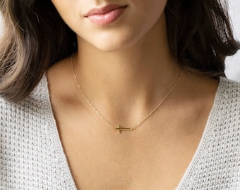 May include: A delicate gold chain necklace with a small, simple cross pendant.