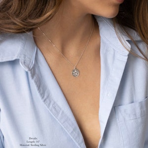 Może przedstawiać: Srebrny naszyjnik z małym, okrągłym wisiorkiem przedstawiającym anioła. Naszyjnik ma długość 40,6 cm i jest wykonany ze srebra pr&oacute;by 925. Szczeg&oacute;ły: Długość: 40,6 cm Materiał: Srebro pr&oacute;by 925