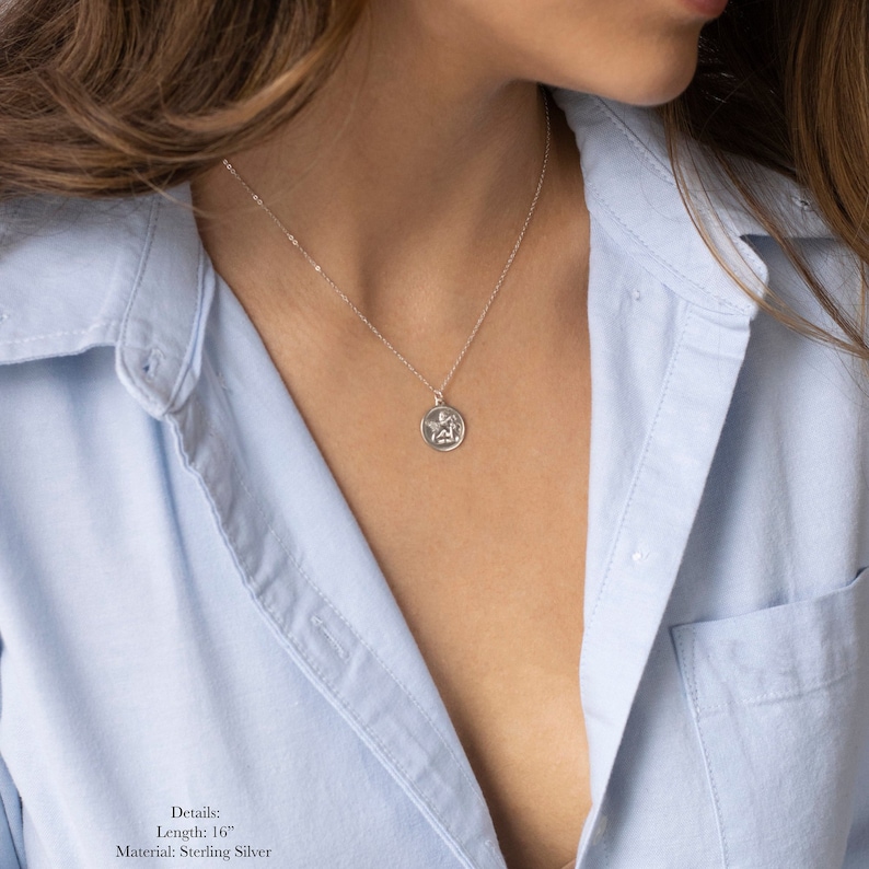 Może przedstawiać: Srebrny naszyjnik z małym, okrągłym wisiorkiem przedstawiającym anioła. Naszyjnik ma długość 40,6 cm i jest wykonany ze srebra pr&oacute;by 925. Szczeg&oacute;ły: Długość: 40,6 cm Materiał: Srebro pr&oacute;by 925