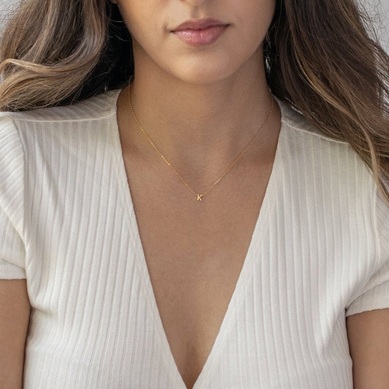 May include: A gold chain necklace with a small letter K pendant.