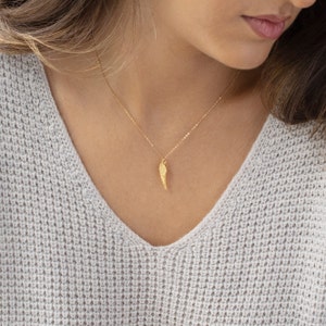 May include: A gold chain necklace with a delicate gold wing pendant.