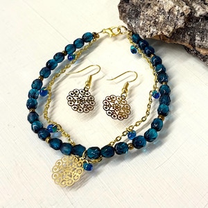 May include: A set of teal blue glass bead bracelet and earrings with gold filigree charms. The bracelet has two strands of gold chain with teal blue glass beads.