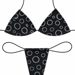 May include: A black bikini set featuring a silver circular pattern. The top consists of two triangular cups with thin black string ties, and the bottom is a thong-style piece with thin black side ties, both decorated with various sized silver rings.