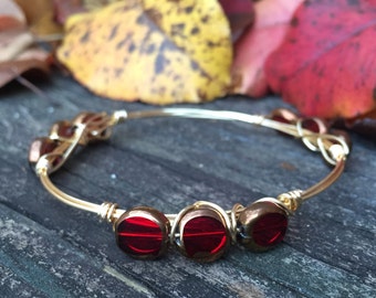 The Red Berry Bangle, three red beads with gold around the edges, wire wrapped on gold wire, bourbon and bowites inspired style