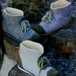 May include: Three pairs of felt boots with green and white laces. The boots are made of wool felt and have a suede toe cap. The boots are sitting on a wooden surface.