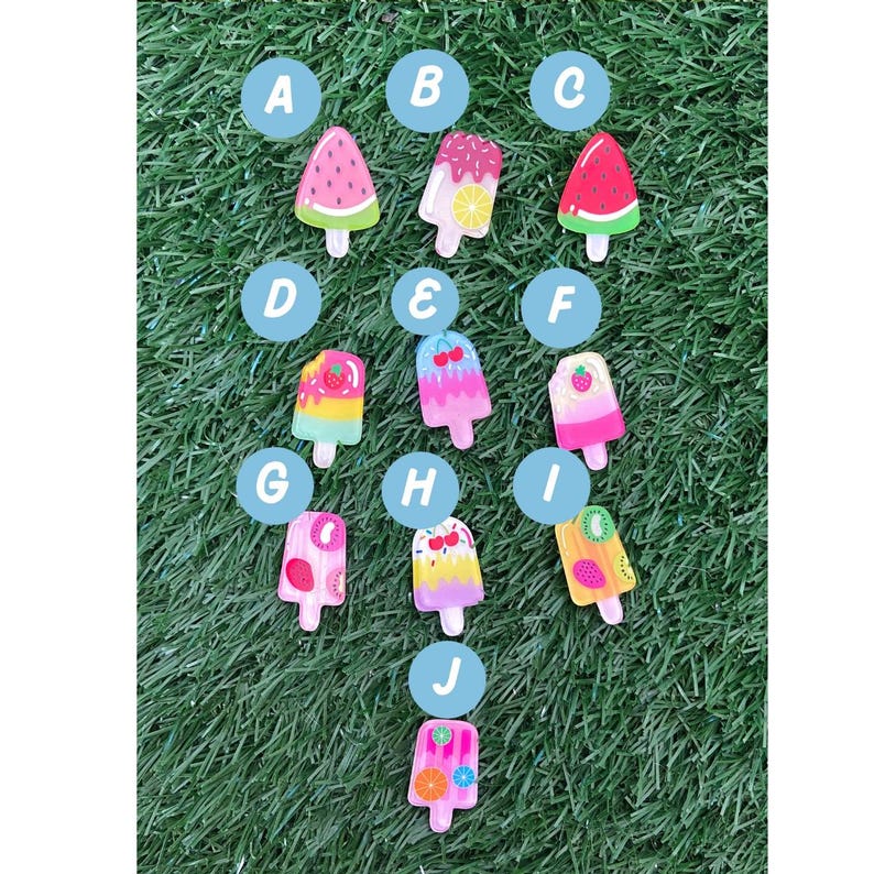 May include: Ten colourful popsicle charms with different fruit designs, labelled A through J. The charms are on a green grassy background.