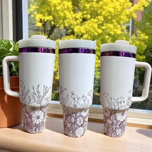 White floral 40oz tumbler with purple flowers around base, durable insulated cup for hot and cold drinks, ideal gift for her