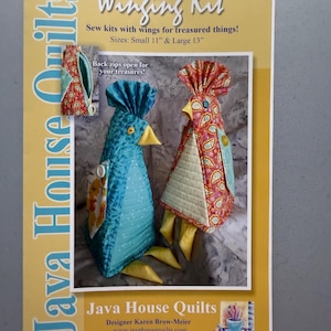May include: A sewing kit cover featuring two bird-shaped designs with wings. The kit includes sizes Small 11" and Large 13". The cover has the text "Winging Kit" and "Java House Quilts". The bird designs are in blue and red with yellow accents.