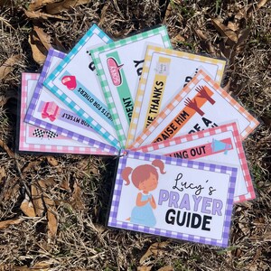 May include: A colourful prayer guide for children, featuring a girl praying and the words "Lucy's Prayer Guide". The guide includes cards with phrases like "For Myself", "Praise Him", and "Sorry".