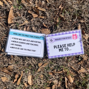 May include: Two laminated cards with a light blue and purple background. The first card has the text "HOW CAN YOU PRAY FOR OTHERS?" and lists four bullet points: "THOSE WHO ARE SICK AND HURTING", "WORLD LEADERS AND TEACHERS", "MY FRIENDS", and "WHO ELSE CAN YOU PRAY FOR?" The second card has the number "6" and the text "REQUEST FOR MYSELF" and "PLEASE HELP ME TO..."