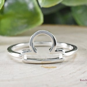 Puede incluir: Anillo de plata con un dise&ntilde;o de s&iacute;mbolo del zod&iacute;aco Libra. El anillo es fino y delicado, con un estilo simple y moderno.
