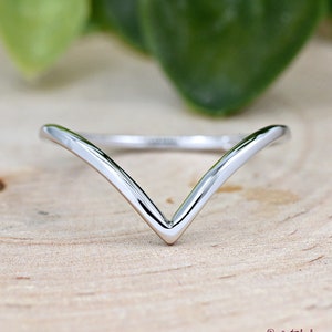 May include: A simple silver ring with a V-shaped design. The ring is made of polished metal and has a smooth finish.