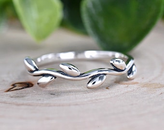 Könnte beinhalten: Ein silberner Ring mit einem zarten Zweigdesign mit kleinen Blättern. Der Ring ist schlicht und elegant.