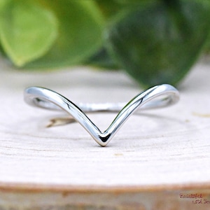 May include: A simple silver ring with a V-shaped design. The ring is thin and delicate, and it would make a great minimalist statement piece.