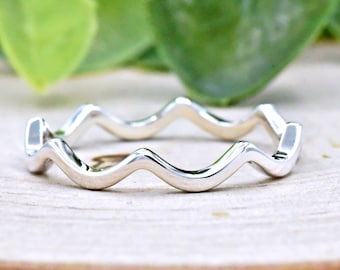May include: A silver ring with a wavy design. The ring is simple and elegant.
