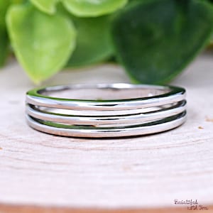 May include: A silver ring with three bands. The ring is smooth and shiny.