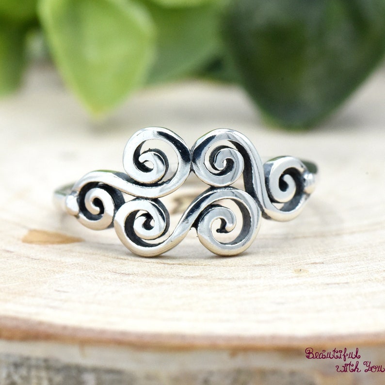 May include: A silver ring with a swirling, abstract design. The ring is made of sterling silver and has a polished finish.