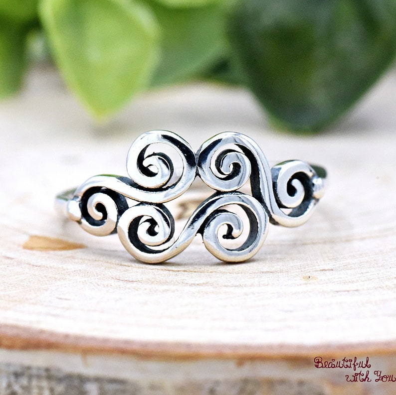 May include: A silver ring with a swirling design. The ring is made of three connected swirls.