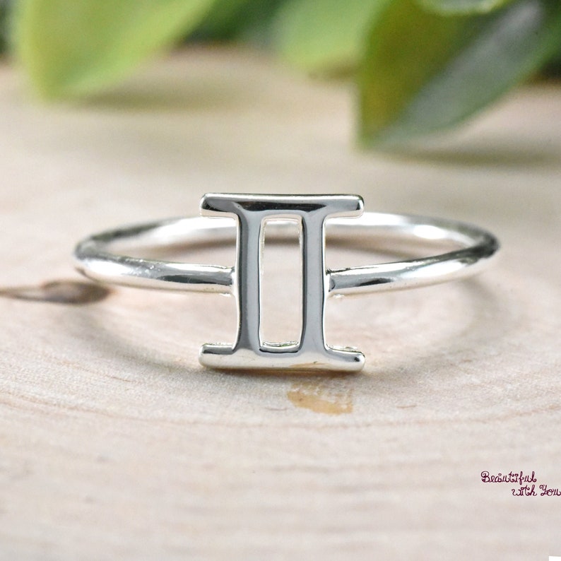 May include: A silver ring with a Gemini zodiac symbol. The ring is simple and elegant.
