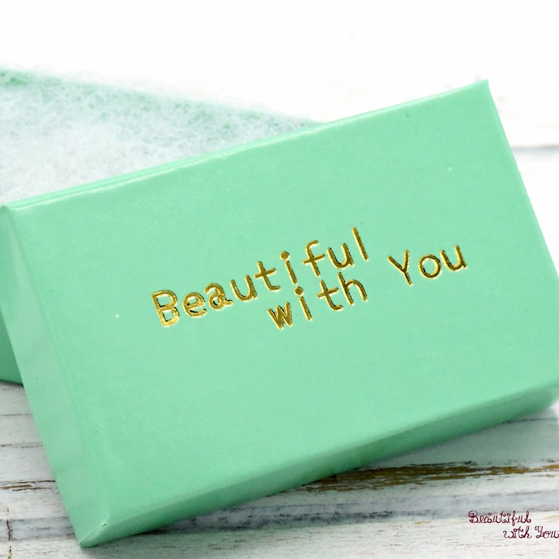 May include: A light green gift box with the words "Beautiful with You" in gold lettering.