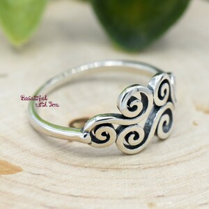 May include: A silver ring with a swirling design. The ring is made of sterling silver and has a polished finish.