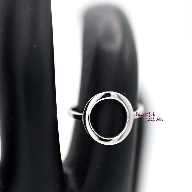 May include: A silver ring with a large, round, open circle design.
