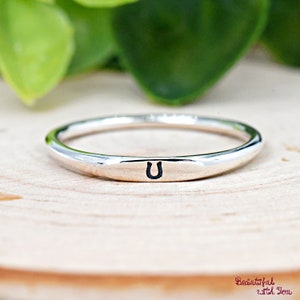 May include: A silver ring with a flat band and the letter "U" engraved on it.