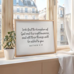 This mockup shows what this unframed Matthew 6 33 Bible verse poster could look like in a frame. It has a white background and gray text. It says seek first the kingdom of God and his righteousness and all these things will be added to you.