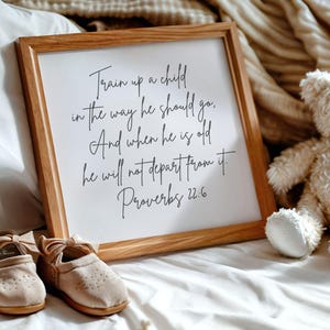 May include: A wooden framed sign with a white background and black text. The text reads "Train up a child in the way he should go. And when he is old he will not depart from it. Proverbs 22:6".