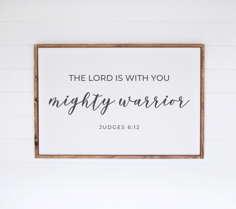 May include: A framed sign with the text "The Lord is with you mighty warrior" and the scripture reference "Judges 6:12".